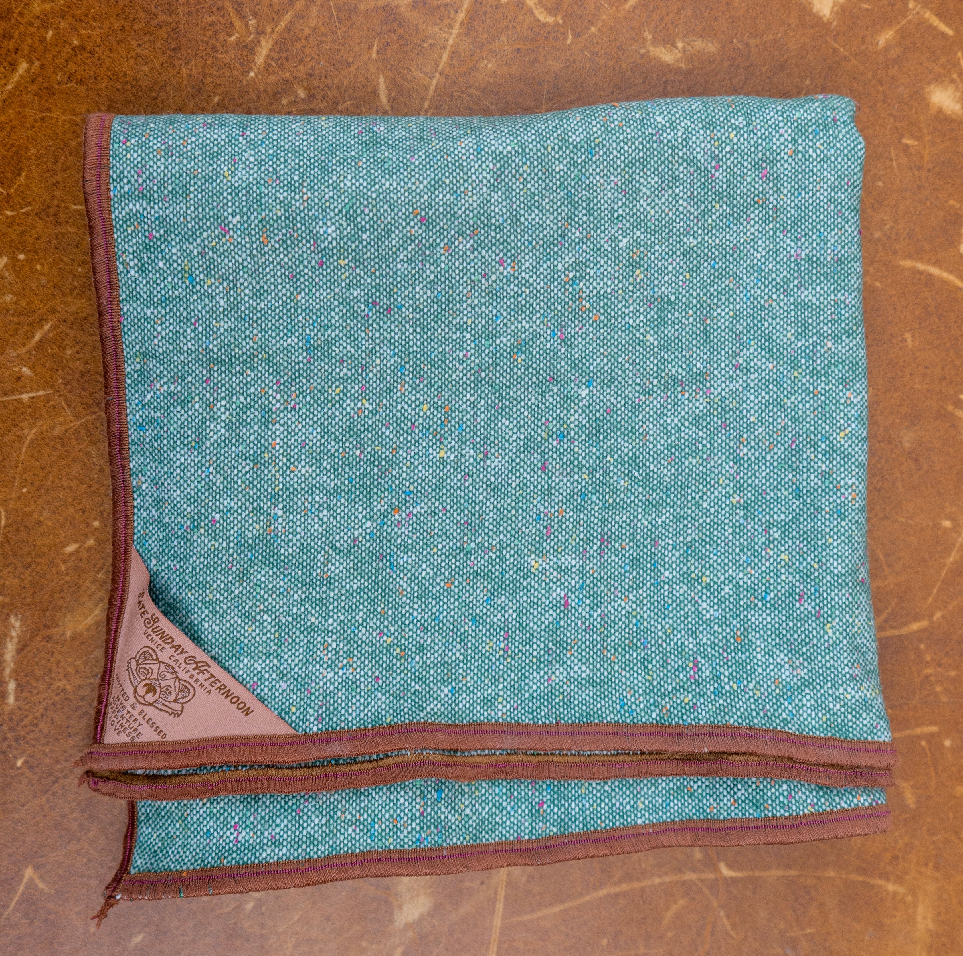 Folded teal fabric with brown border on a scratched LEATHER surface
