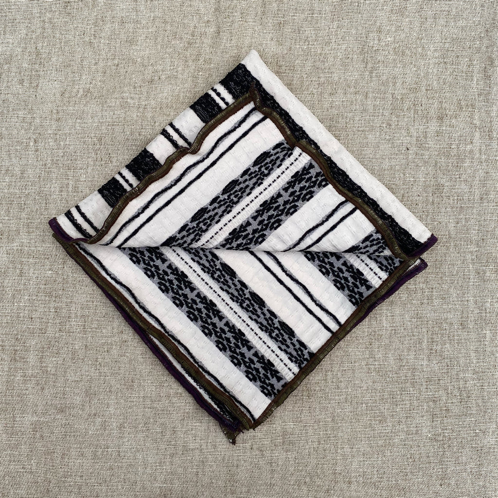 a handkerchief shown folded to reveal both reversible patterns; black and white stripe motifs